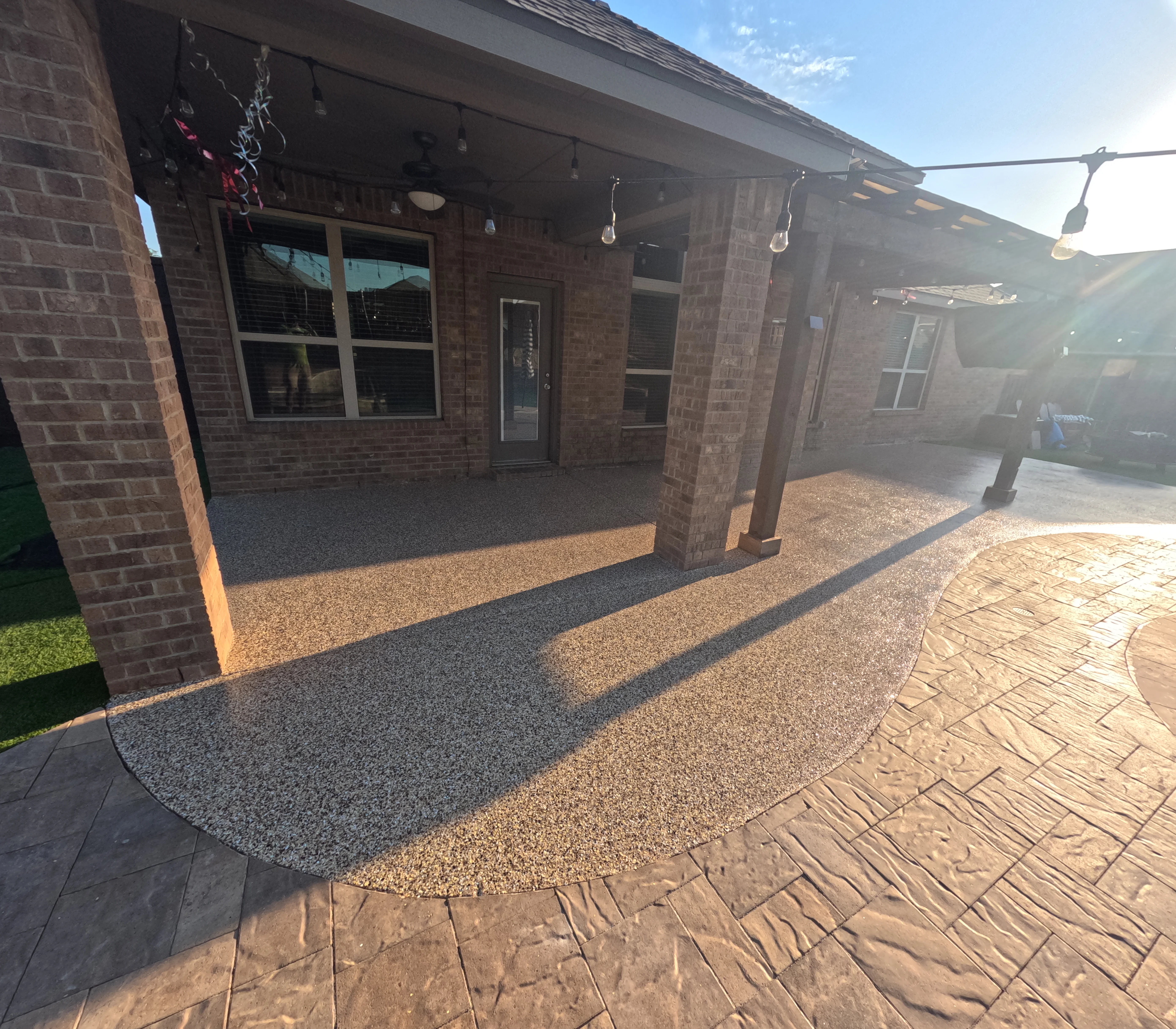 Stamped concrete patio with decorative gravel sections and brick home exterior