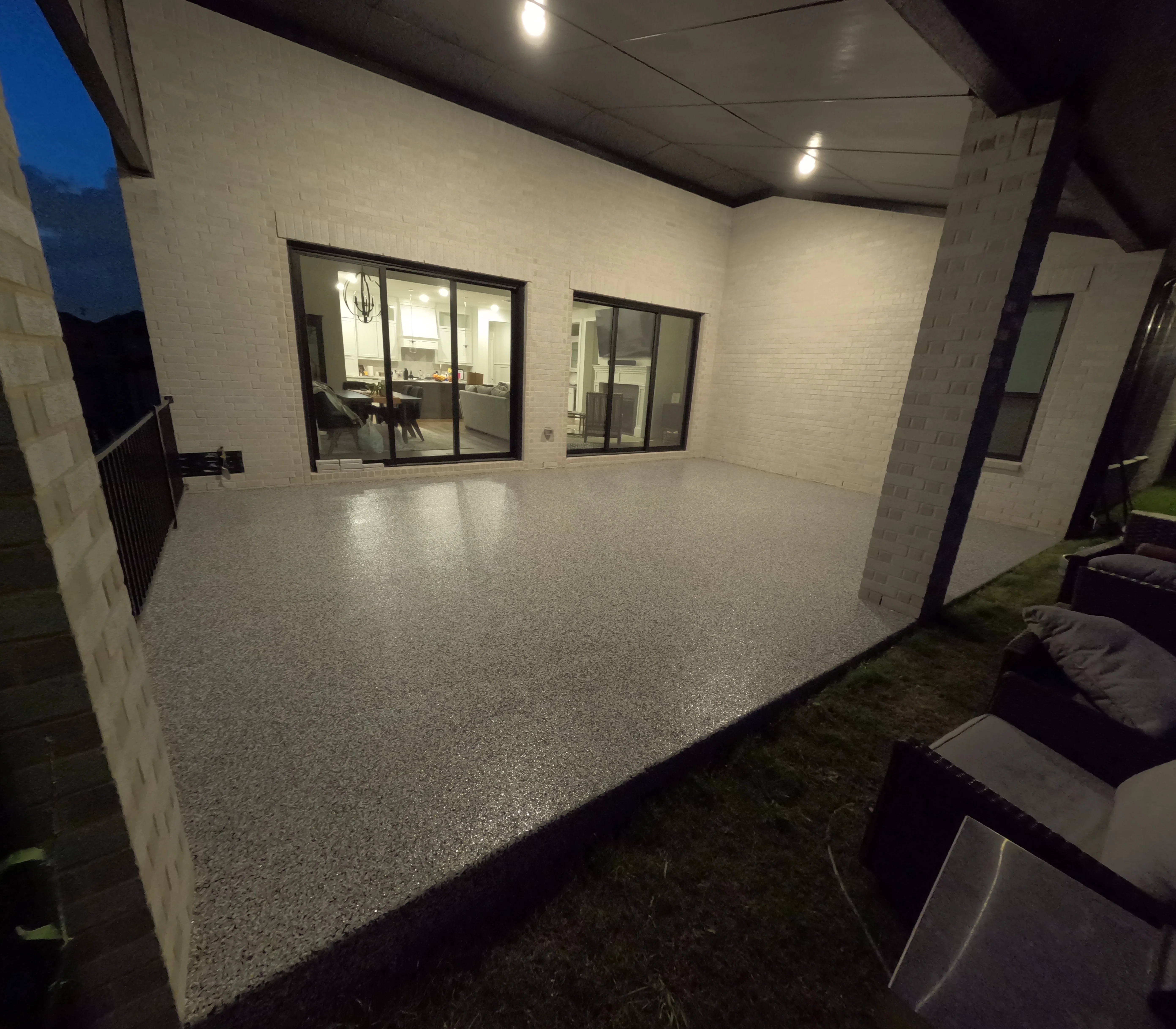 Polished concrete patio with LED lighting and black-framed glass doors at night