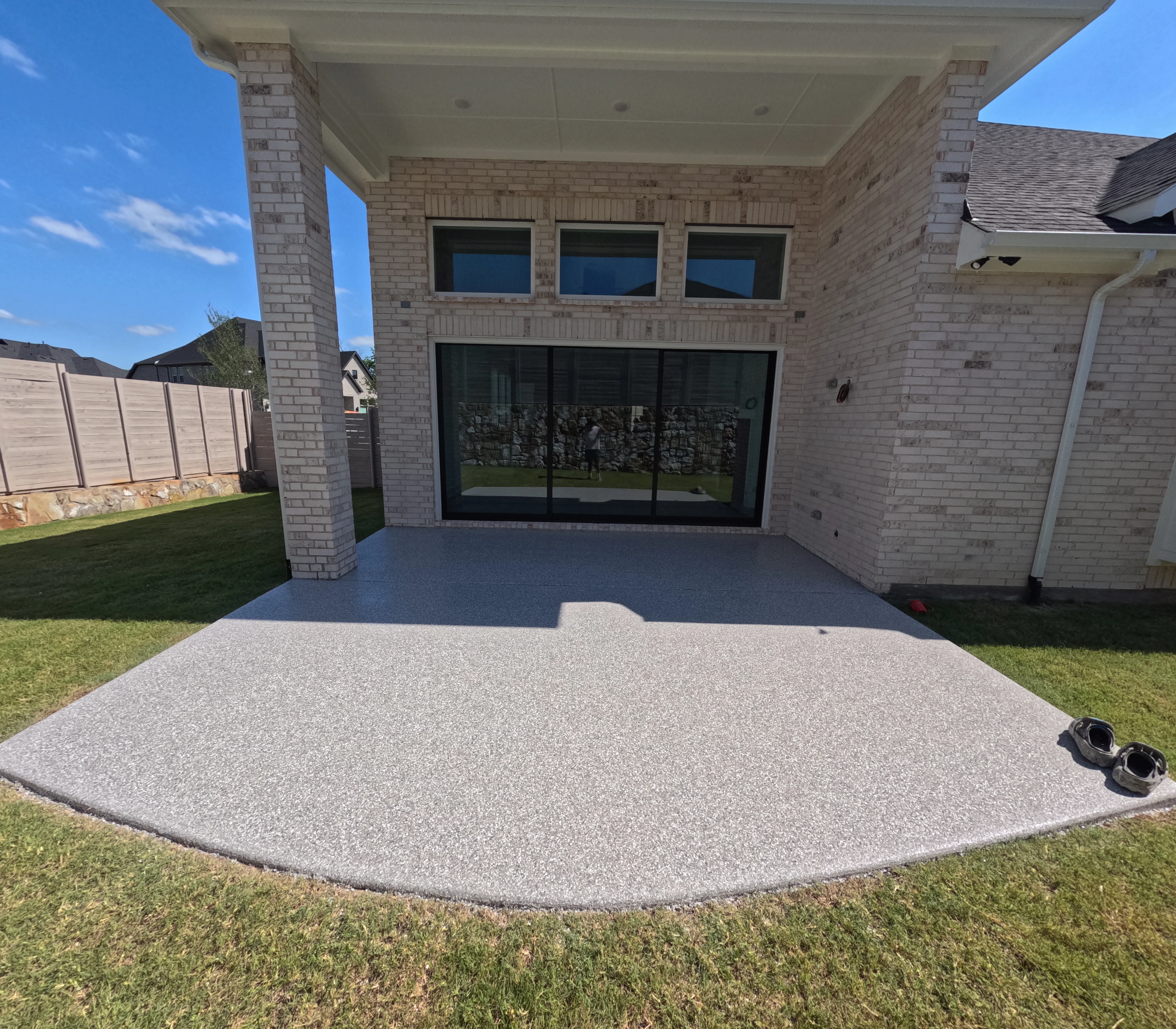 Light gray decorative concrete patio with rounded edges beneath covered brick patio structure