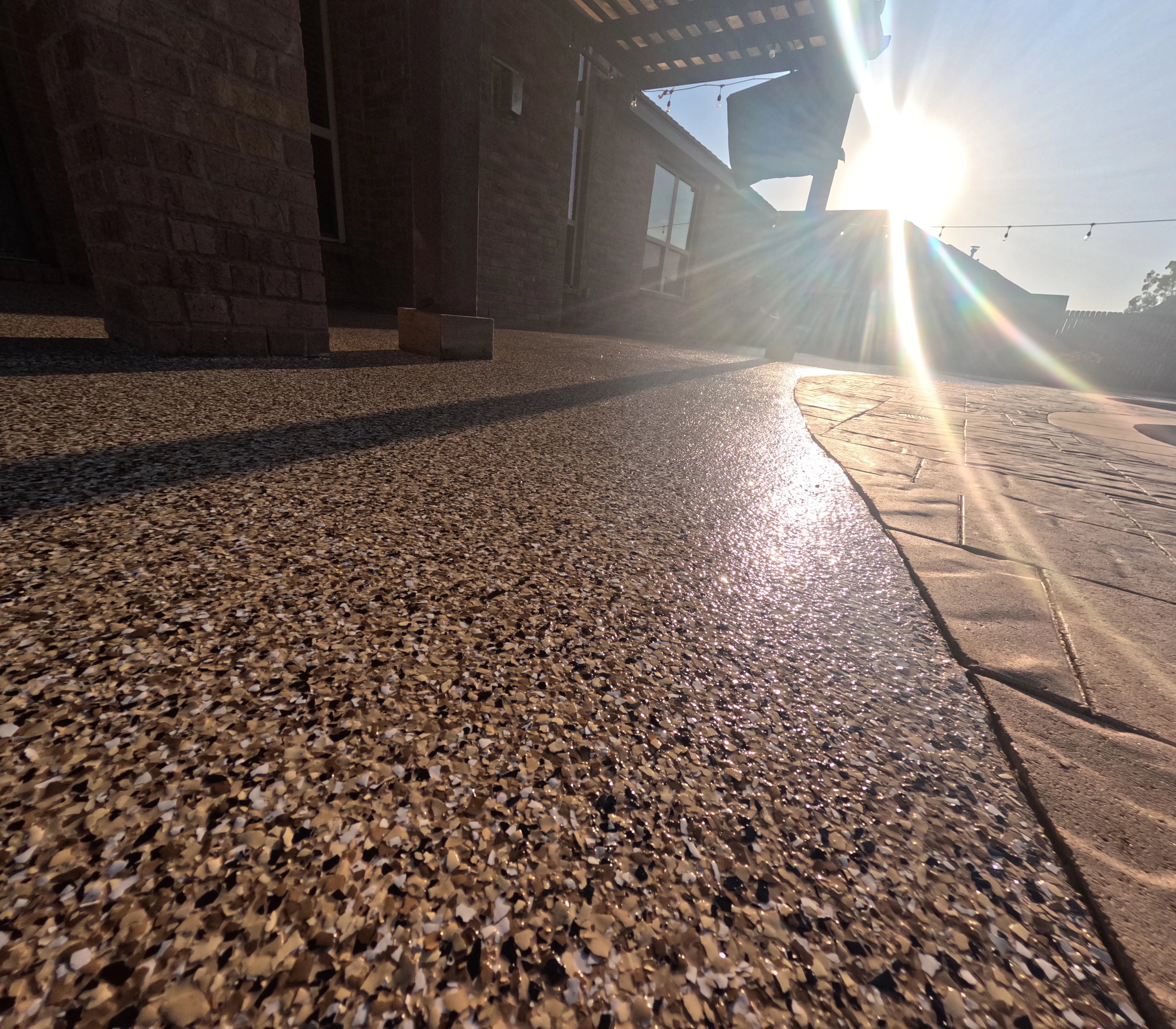 Polished concrete patio with exposed aggregate finish and wood deck transition