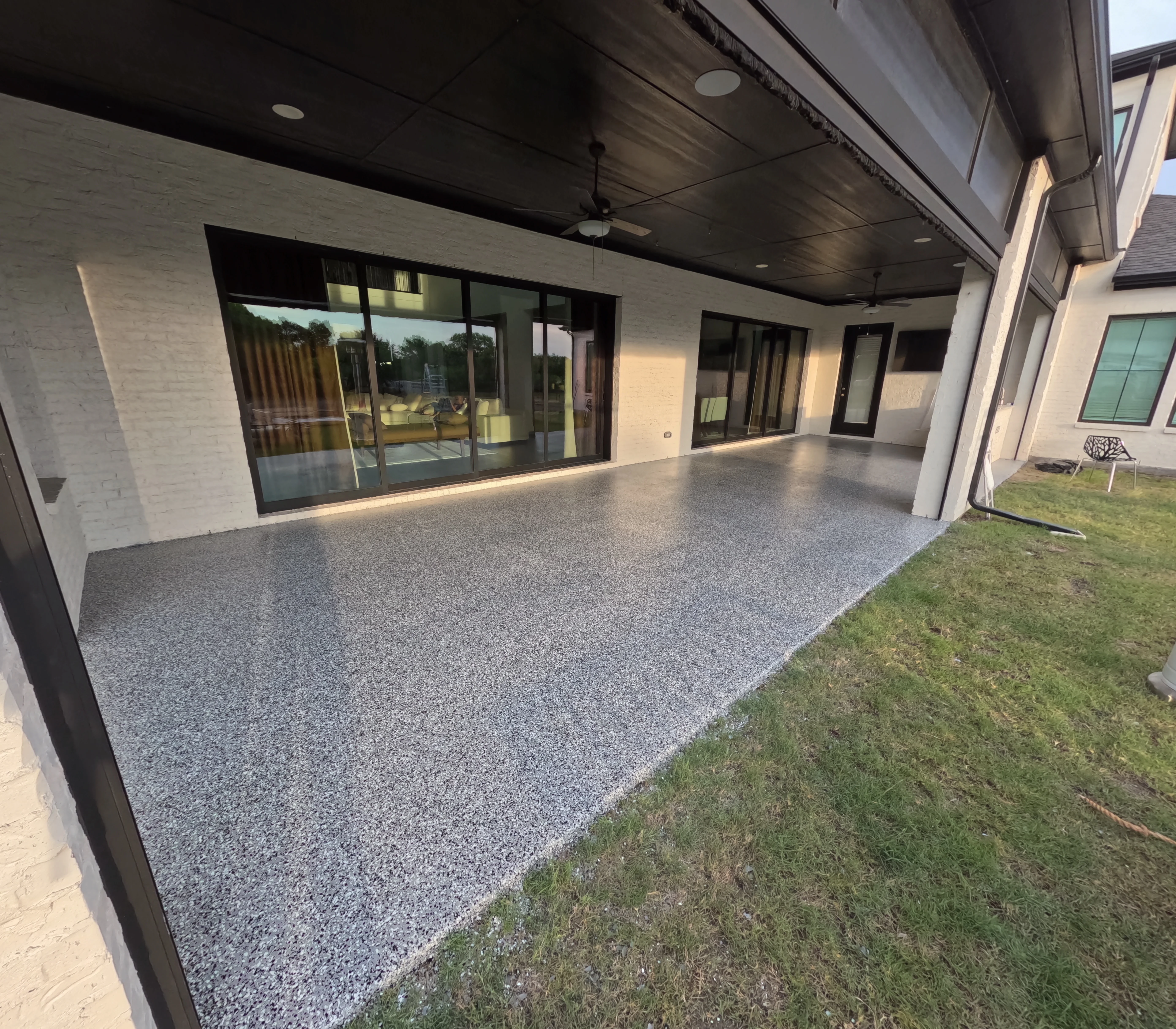 Polished gray aggregate patio with modern home and sliding glass doors